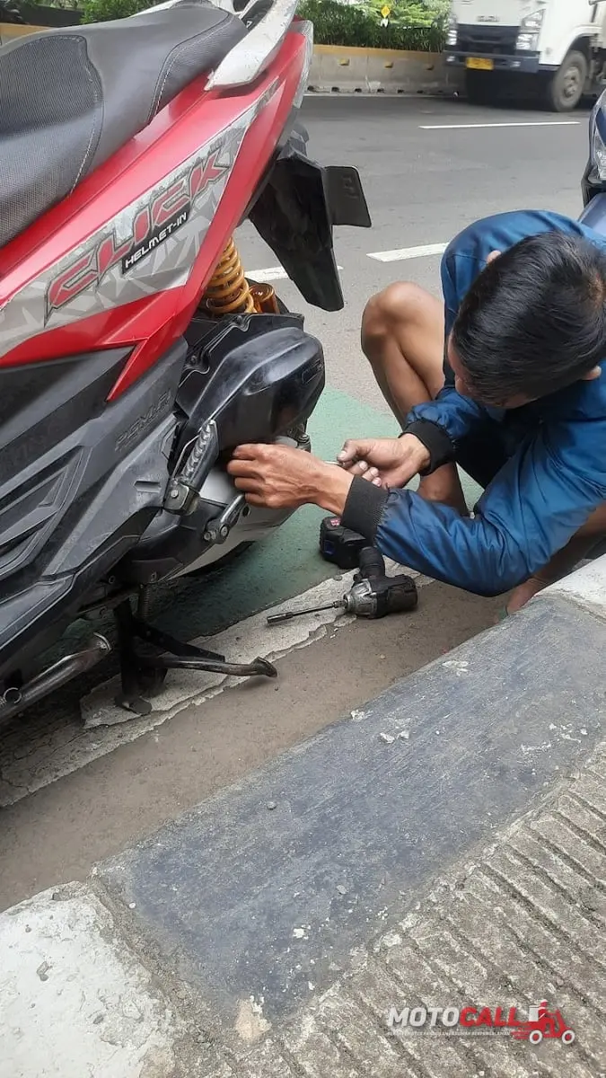 Montir MotoCall membersihkan dan menyetel karburator motor di lokasi pelanggan