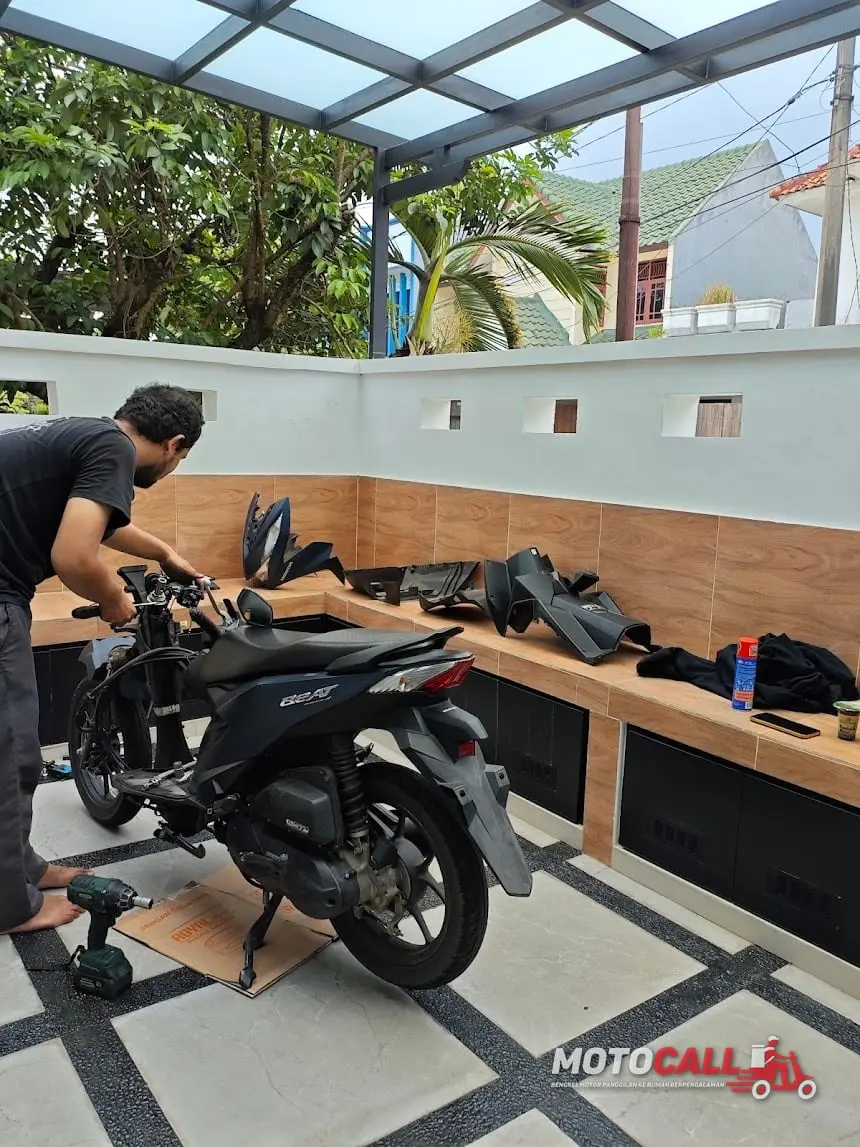 Montir MotoCall mengecek dan mengganti aki motor pelanggan di lokasi