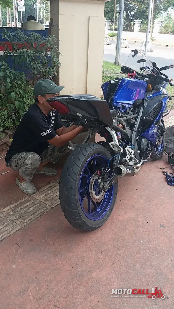 Montir MotoCall memasang aki baru pada motor pelanggan di lokasi