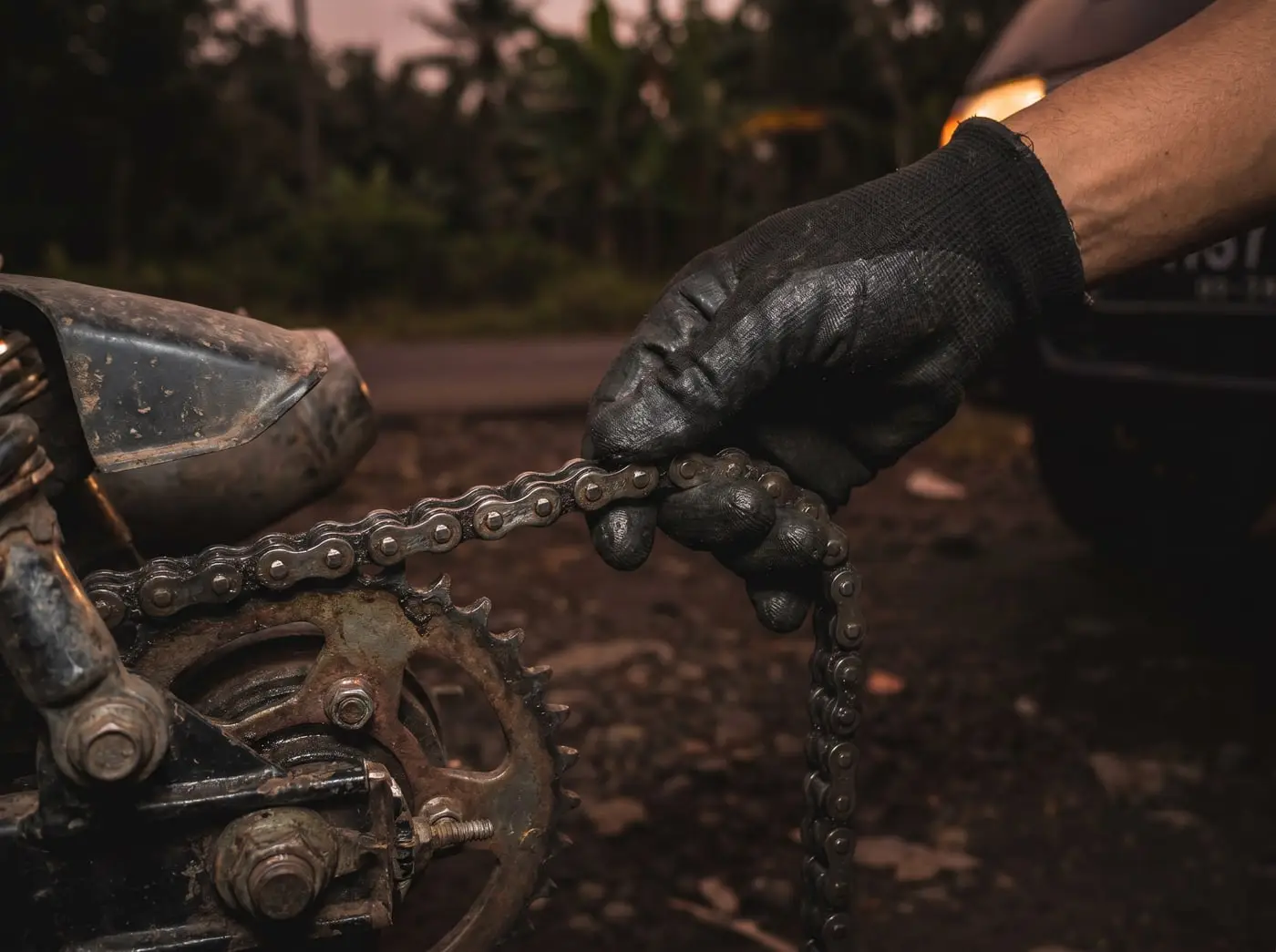 Mekanik memeriksa rantai dan gir motor yang kendor